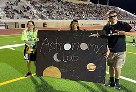  Two girls and a boy holding a sign that reads Astronomy Club